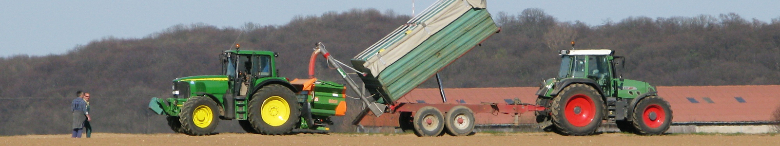 Traktor Anhänger im Feld belädt einen Düngestreuer @Dr.Fritsch